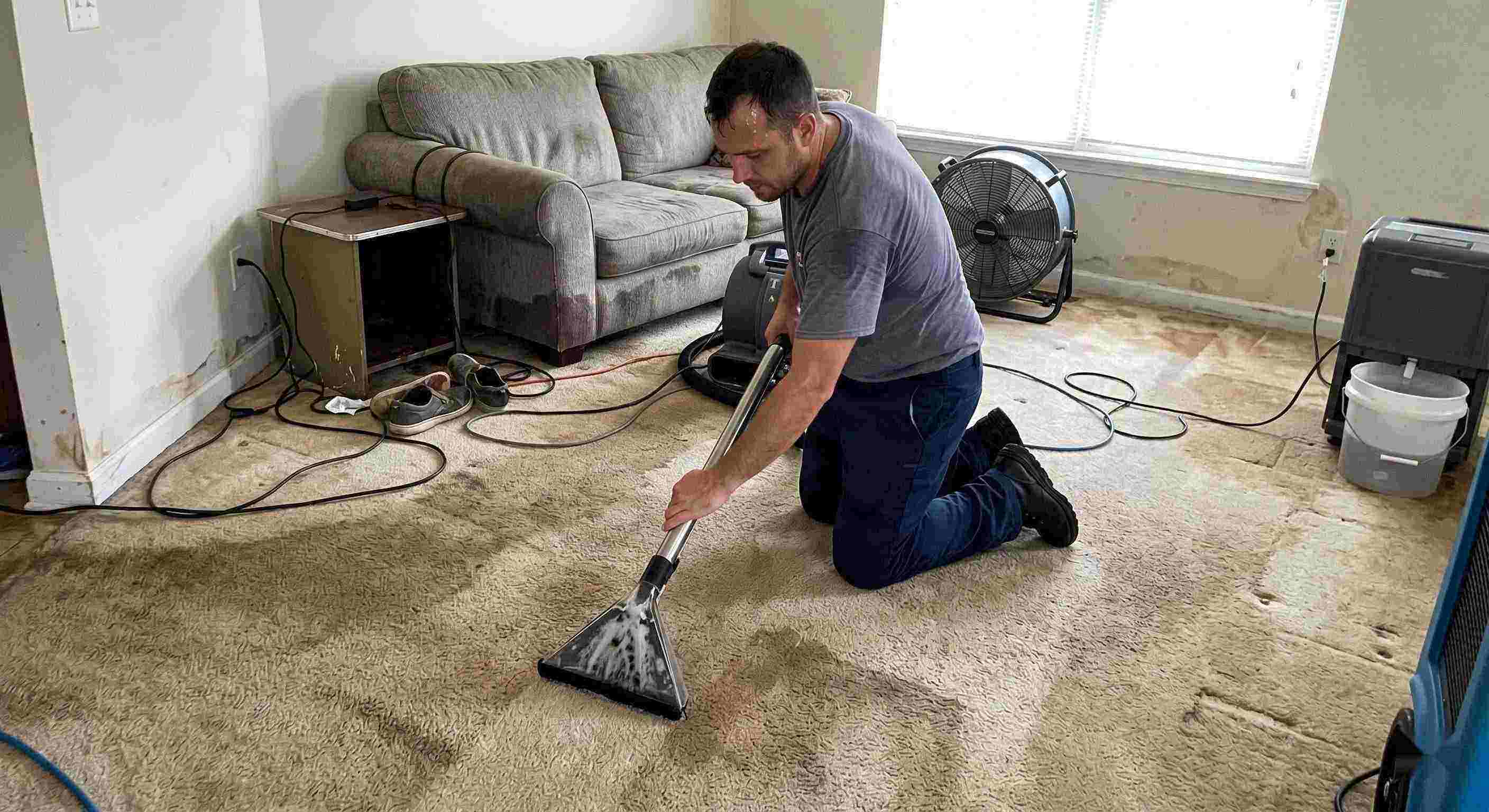 Technician performing carpet water extraction in a residential home using professional equipment after water damage in Salt Lake City