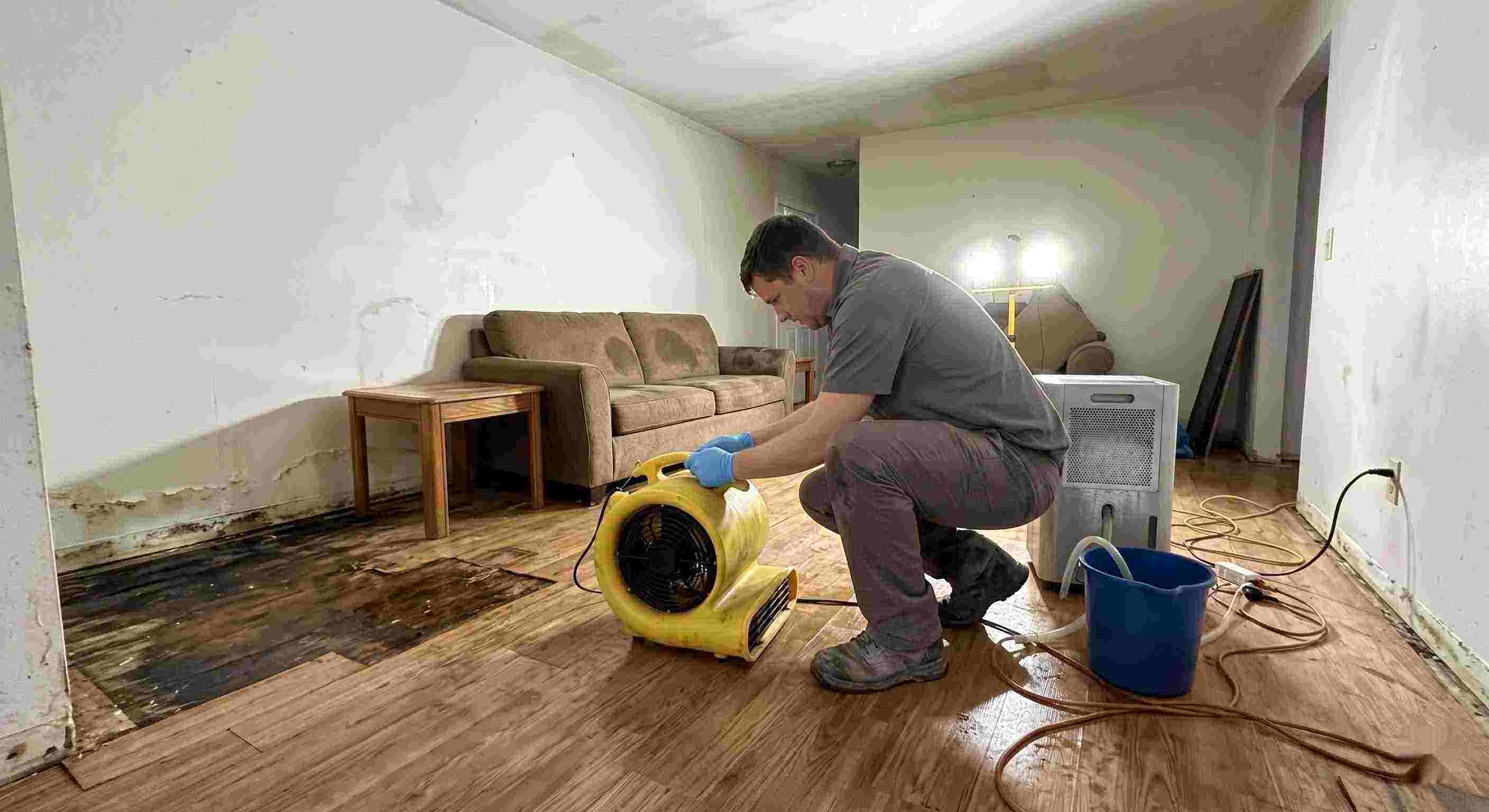 Top-rated water damage restoration technician drying wet floors with equipment during cleanup process in Layton